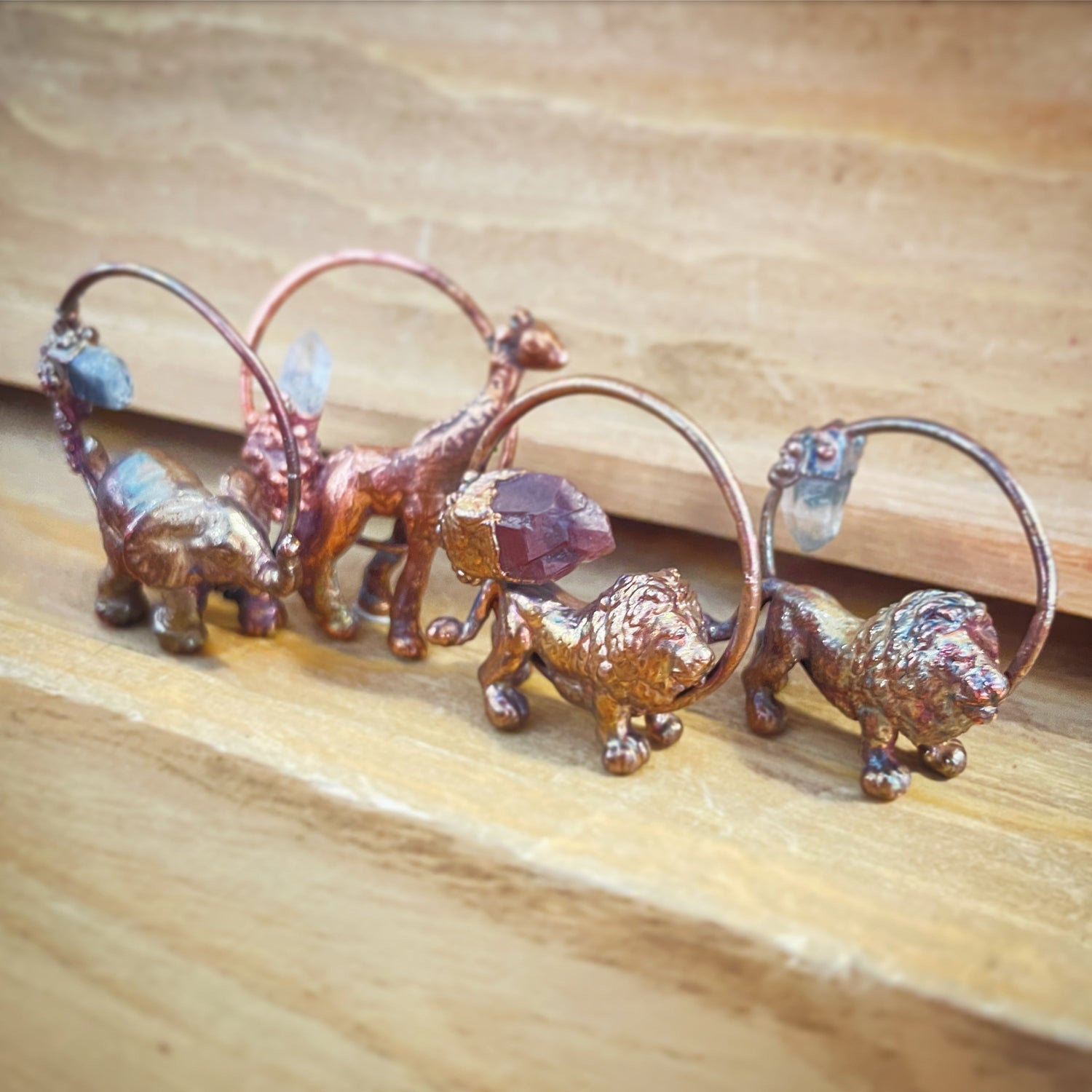 Four copper pendants with tiny animals and crystals. Elephant, Giraffe, and two Lions